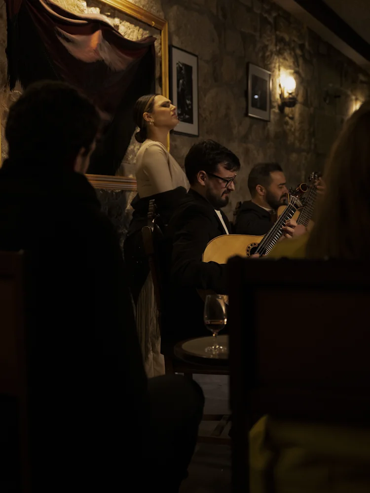 Fadista a cantar com guitarristas num espetáculo de fado no Porto